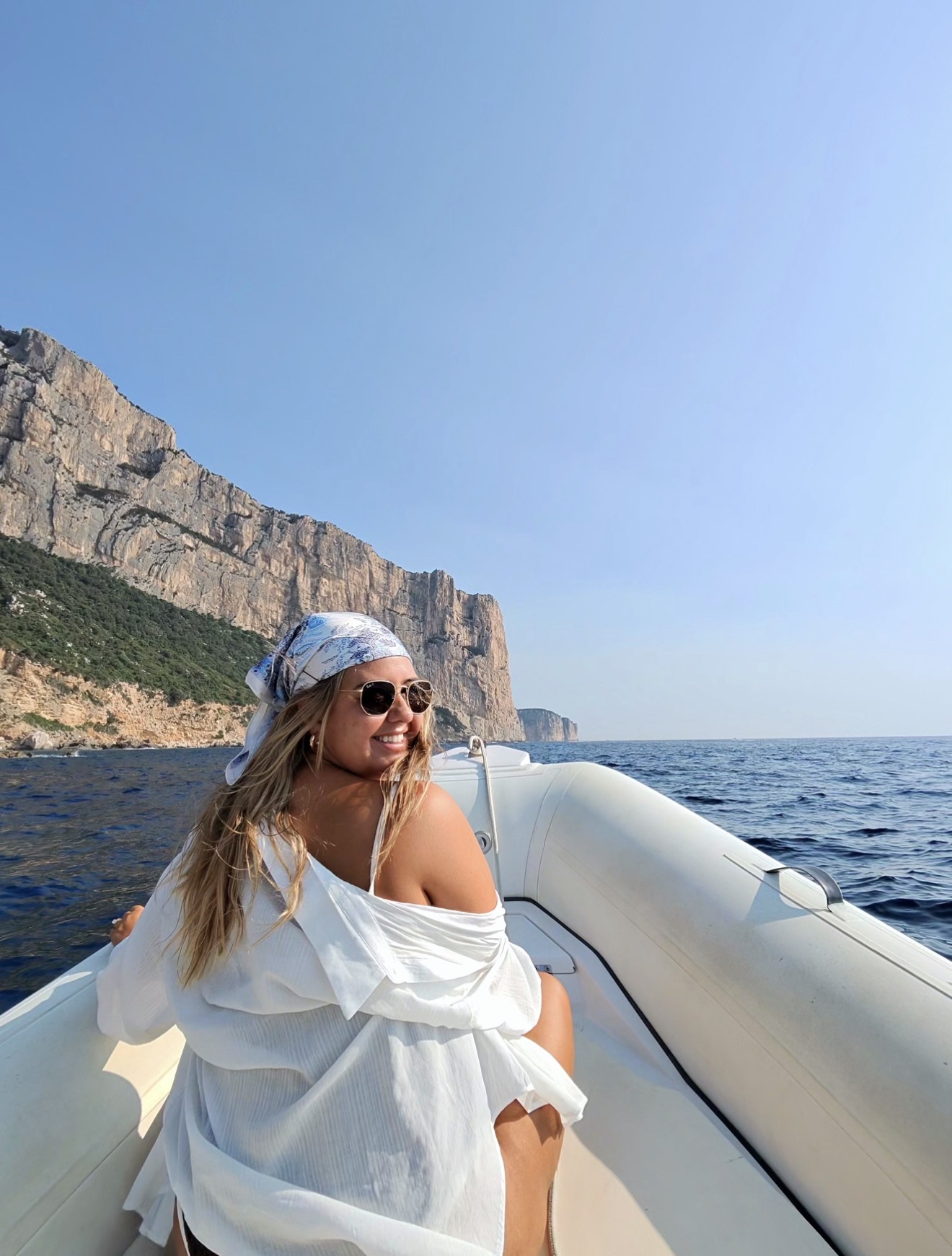 Jamie on the boat we rented, cliffs rising out of the sea behind her