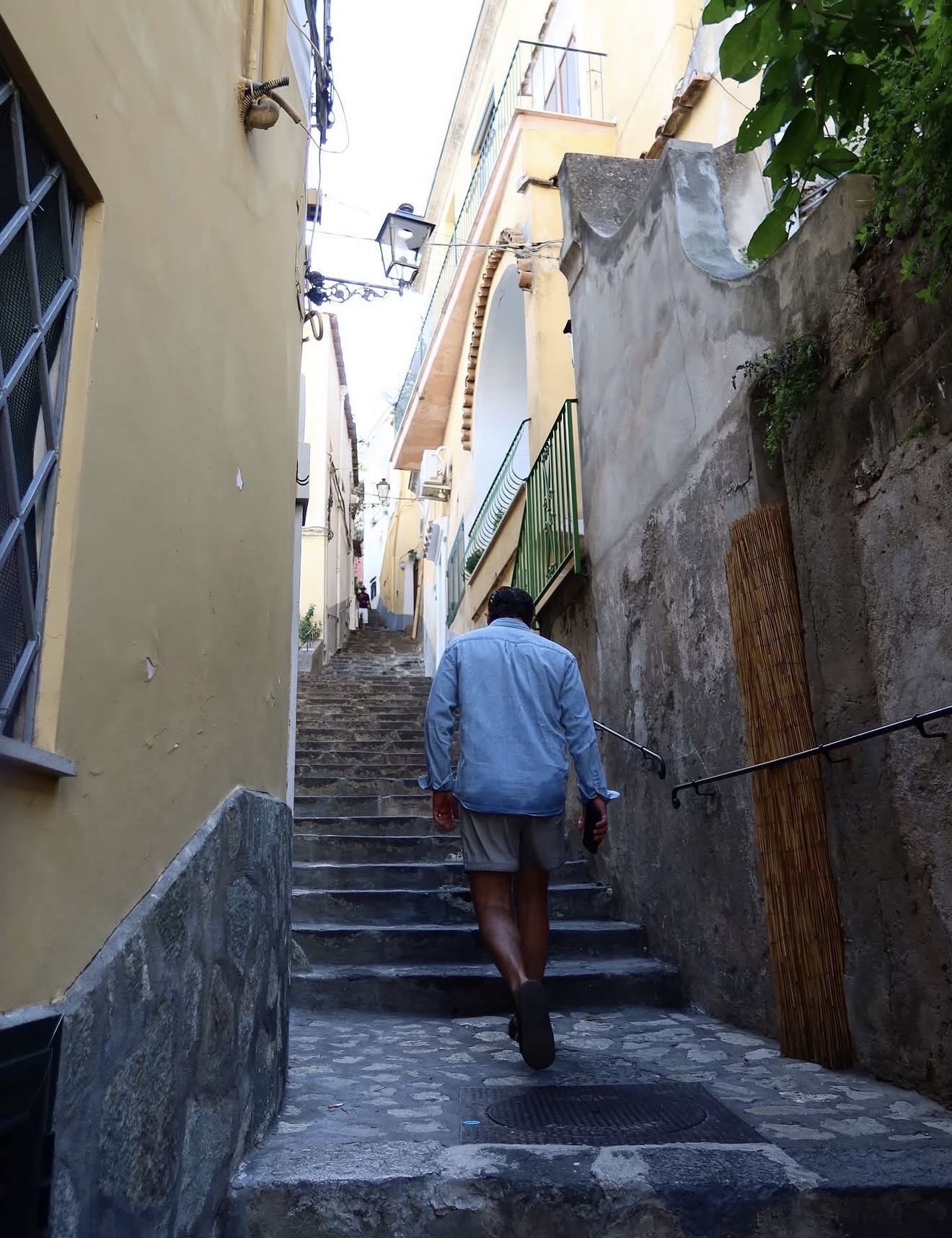 Walking up the stepped lanes of Positano on the Amalfi Coast, pastel walls and a lantern overhead